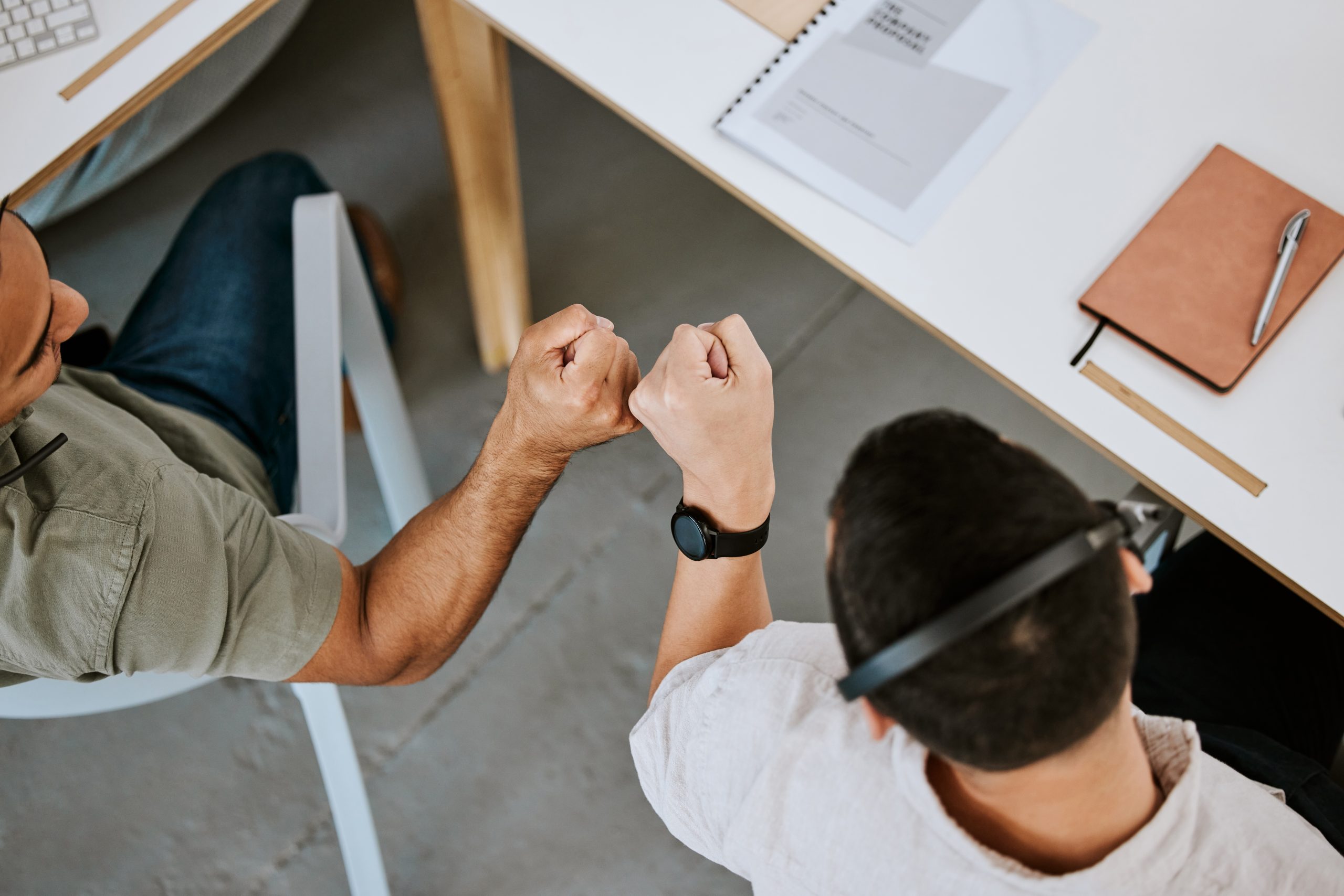 Excited call centre agents, fist bump and celebrating deal, promotion and sale from above in office. Motivated, happy and successful telemarketing colleagues or customer support operators cheering